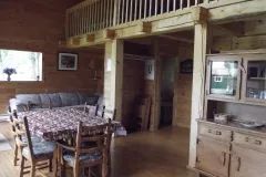 The open area of the cabin includes a dining room, a living room, and a wooden mezzanine.