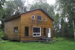 Vue extérieure du chalet 10 entouré d'arbres avec une table de pique-nique à proximité.