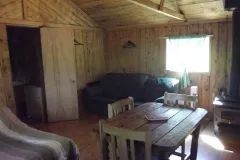 Vue de l'aire de vie principale du chalet, incluant une table à manger et un coin salon.