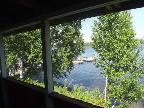 Vue sur le lac et le quai depuis la véranda grillagée du chalet.