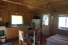 Vue d'ensemble de la cuisine et de la salle à manger du chalet 5 avec ses murs en bois.