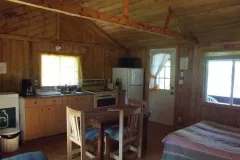 Vue d'ensemble de la cuisine et de la salle à manger du chalet 5 avec ses murs en bois.