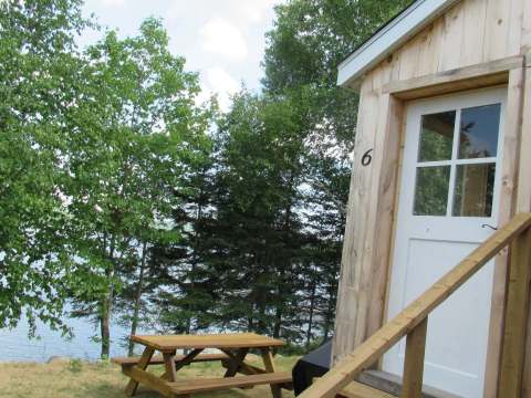 Entrance to cabin number six with outdoor picnic table and forest view.