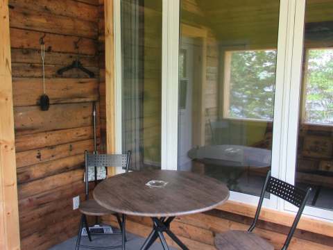 A small table and two chairs are set up on the covered porch of cottage 6.