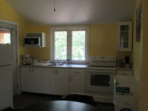 The cottage's functional kitchen includes a stove, a refrigerator, and a workspace.