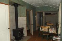 The living area of chalet 7 includes a dining table and a wood stove.