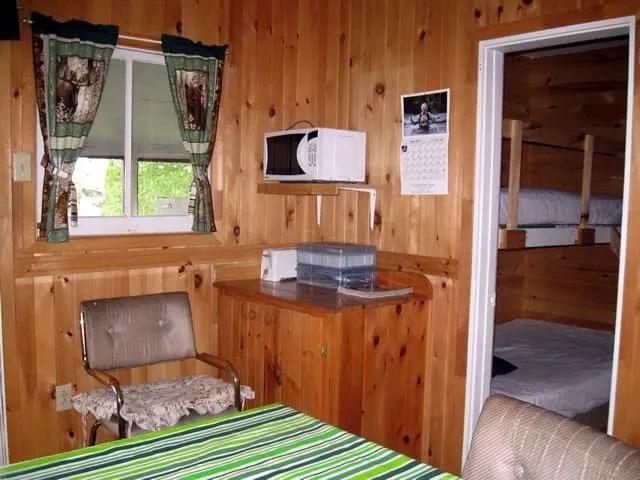 Interior view of the cottage featuring a kitchenette with a microwave and a bedroom with bunk beds.