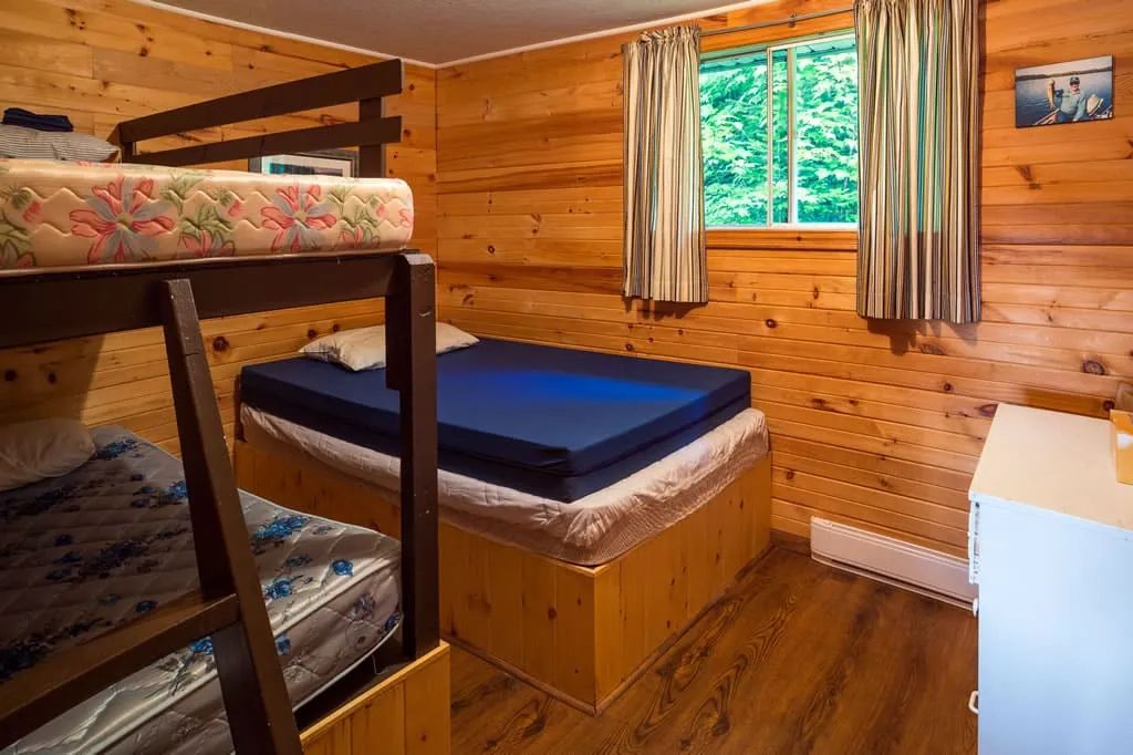 This bedroom in cabin 6 features a double bed and a wooden bunk bed.