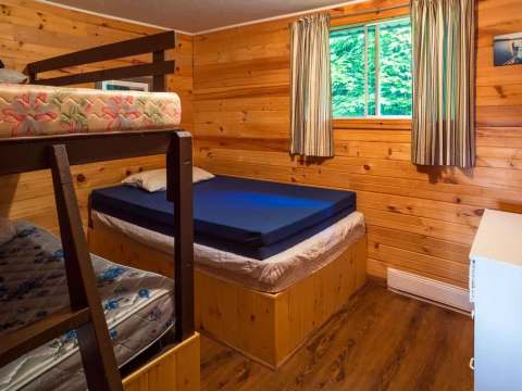 This bedroom in cabin 6 features a double bed and a wooden bunk bed.