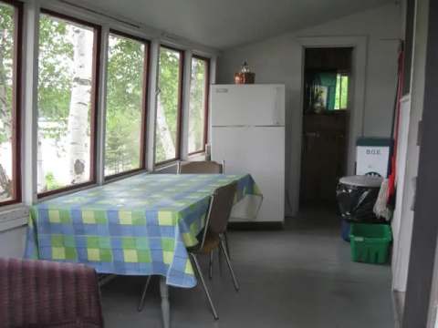 The veranda of cottage 3 includes a dining table and a refrigerator with a view of the forest.
