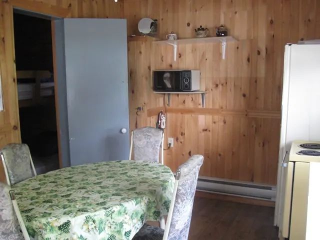 The cottage kitchen and dining area featuring wood walls and functional amenities.