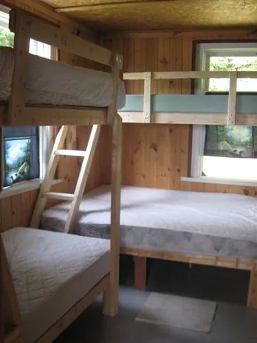 This cottage bedroom features wooden bunk beds with mattresses.