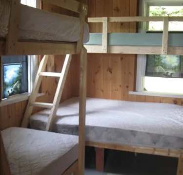 This cottage bedroom features wooden bunk beds with mattresses.
