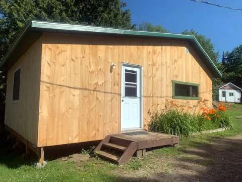 Exterior view of cottage 2 featuring its natural wood siding and front entrance steps.