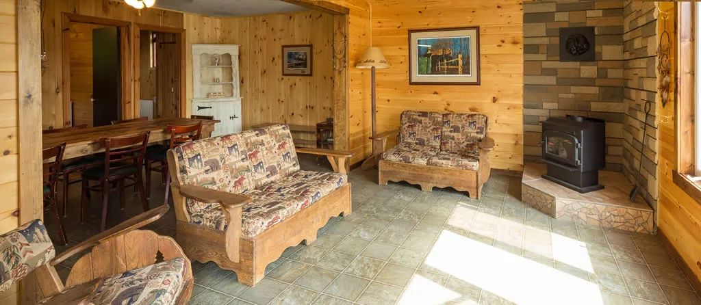 The cottage's living room and dining area feature rustic wooden furniture and a wood stove.