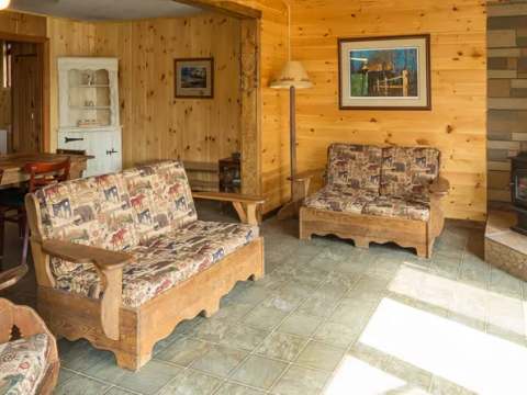 The cottage's living room and dining area feature rustic wooden furniture and a wood stove.