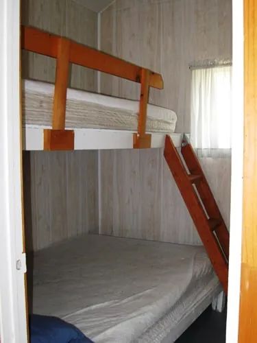A bedroom in the cabin features a bunk bed with a wooden frame.