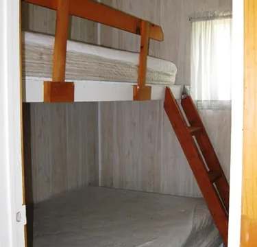 A bedroom in the cabin features a bunk bed with a wooden frame.