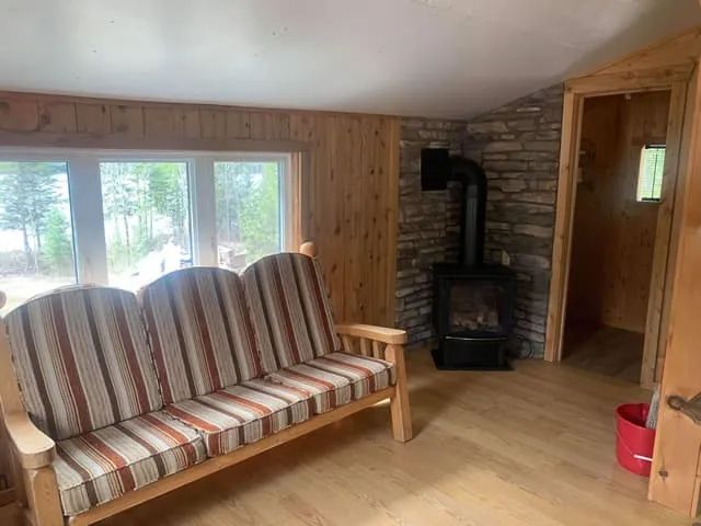 The cottage living room is equipped with a comfortable sofa and a wood stove.