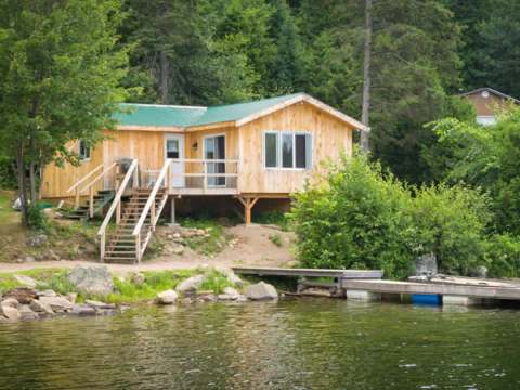 Cottage 6 is located by the lake with a private dock and a wooden deck.