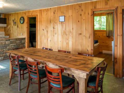 The dining room of cabin 6 features a large wooden table and comfortable chairs.