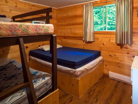 This bedroom in chalet 6 is furnished with bunk beds and a double bed.