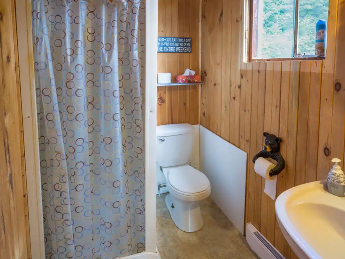 This cabin bathroom features an enclosed shower and wood-paneled walls.