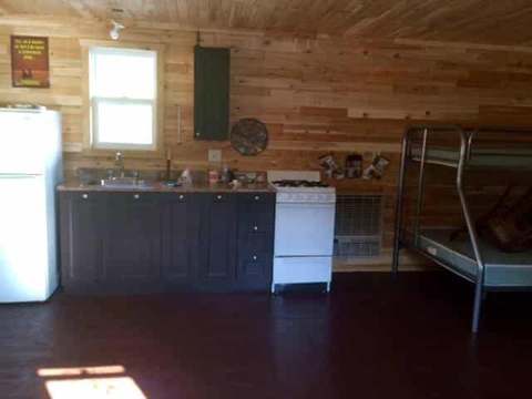Cette cuisine de chalet flottant comprend un réfrigérateur, une cuisinière et un lit superposé.