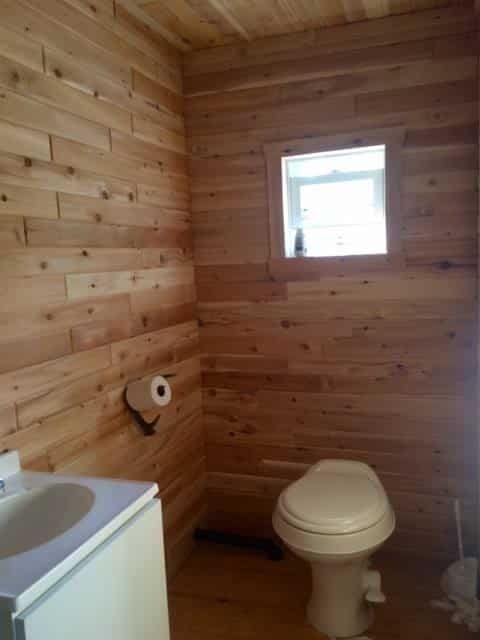 Vue de la salle de bain en bois avec toilette et lavabo à l'intérieur du chalet flottant.