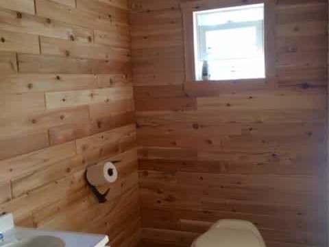 Vue de la salle de bain en bois avec toilette et lavabo à l'intérieur du chalet flottant.