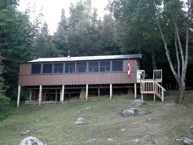 Le chalet Outpost est une construction rustique sur pilotis entourée par la forêt.
