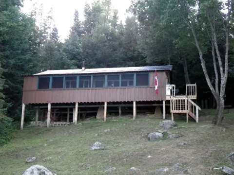 Le chalet Outpost est une construction rustique sur pilotis entourée par la forêt.
