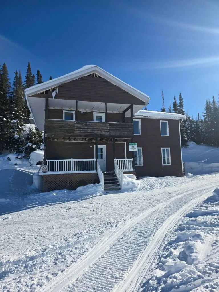 Vue extérieure de La Petite Auberge sous une belle journée d'hiver enneigée.