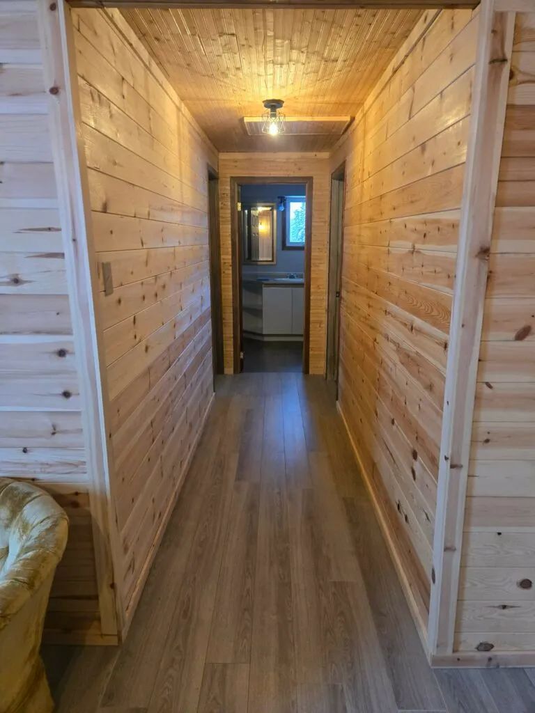Un couloir en bois mène vers la salle de bain de La Petite Auberge.