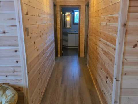 Un couloir en bois mène vers la salle de bain de La Petite Auberge.