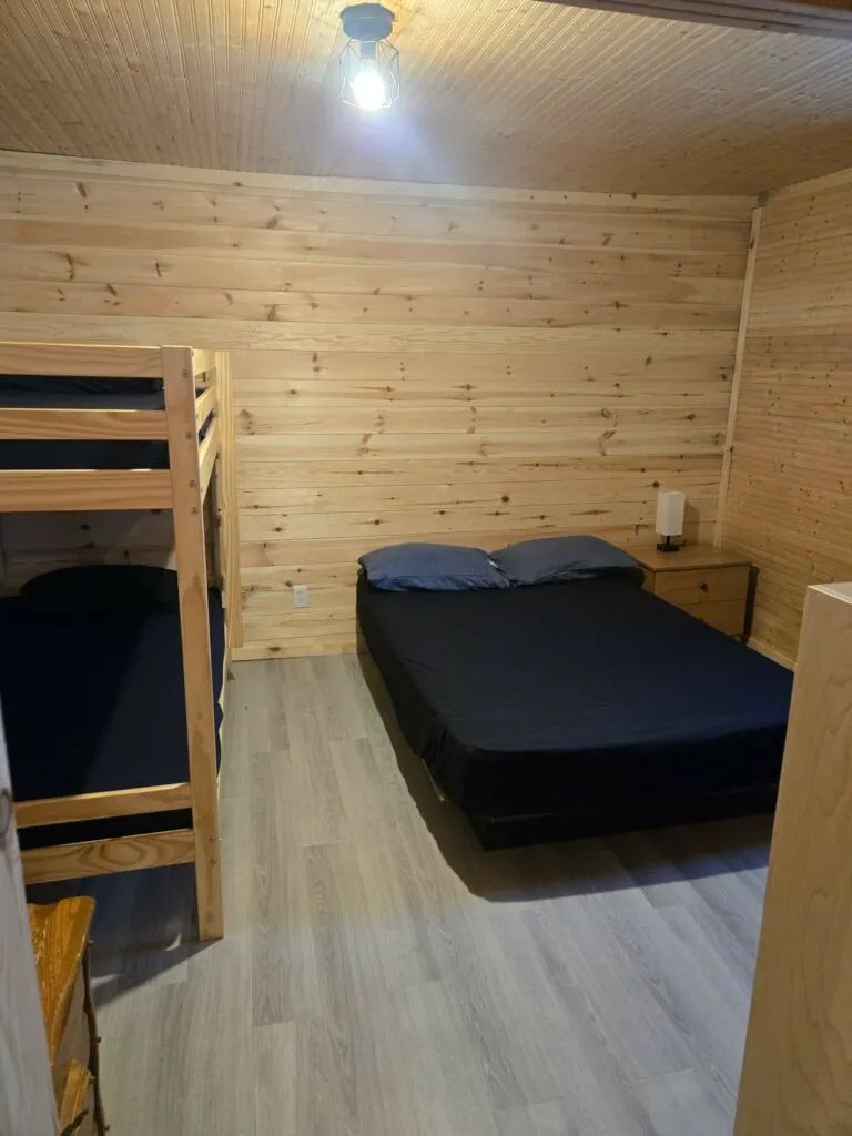 Cette chambre de La Petite Auberge comprend un lit double et un lit superposé en bois.