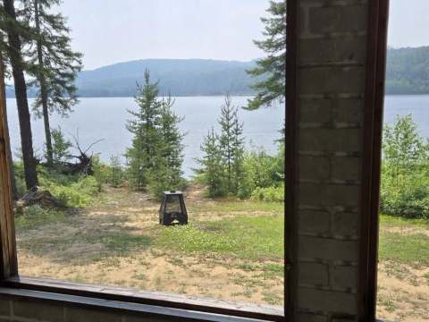 Vue panoramique sur le lac depuis la véranda grillagée du chalet.