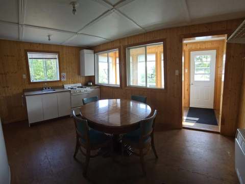 The kitchen and dining area of cabin 5 feature a refrigerator, a stove, and a table.