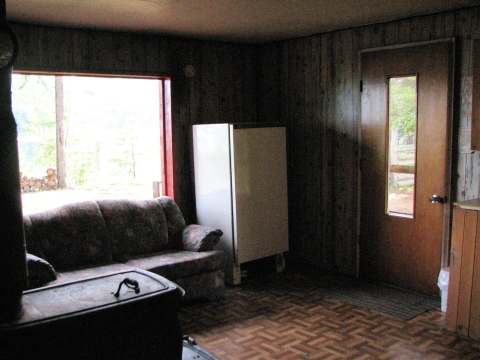 Living area of the cabin featuring a sofa, wood stove, and outdoor view.