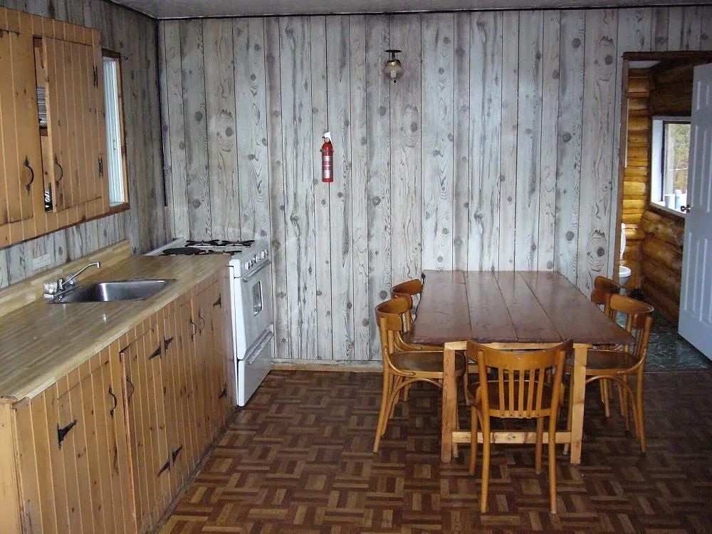 This cabin kitchen features a dining table with chairs and wooden countertops.