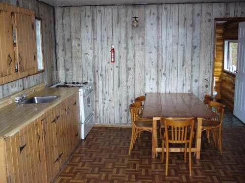 This cabin kitchen features a dining table with chairs and wooden countertops.