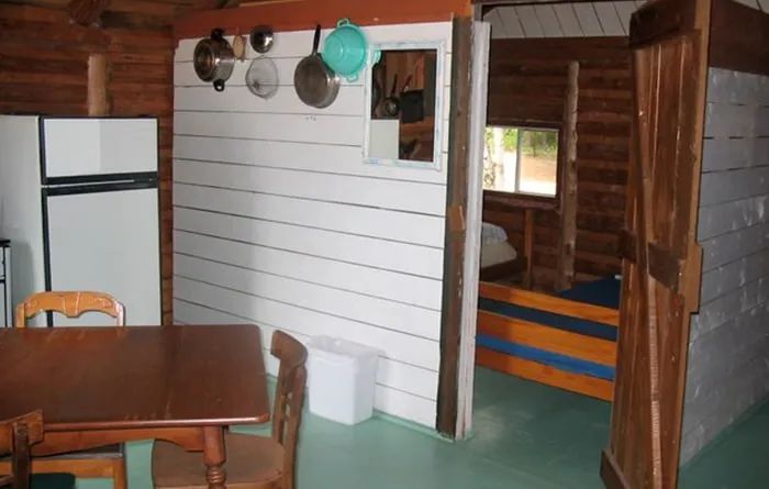 Interior view of the rustic cottage featuring a dining area and an adjoining bedroom.