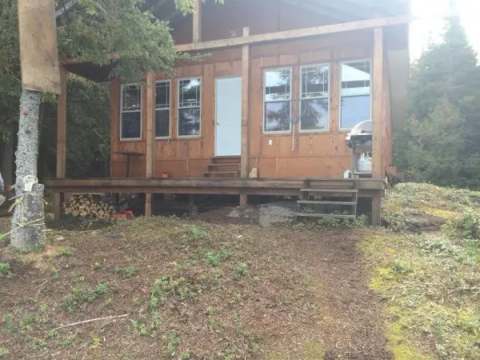 View of the front of the Bapati cabin with its wooden porch and outdoor grill.