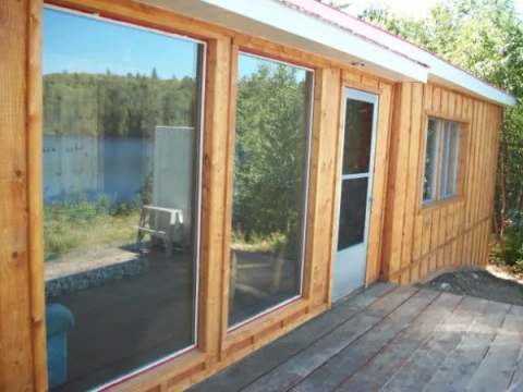 Vue latérale de la façade du camp 1 avec ses grandes fenêtres et sa terrasse en bois.