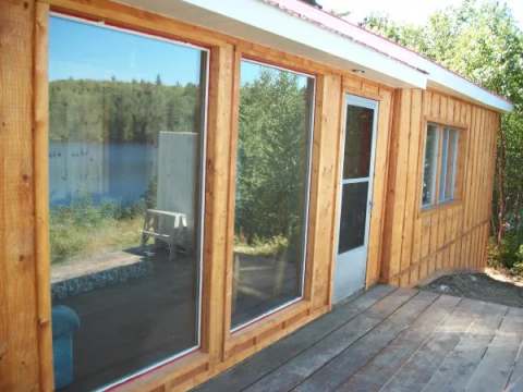 Vue latérale de la façade du camp avec ses grandes fenêtres et sa galerie en bois.