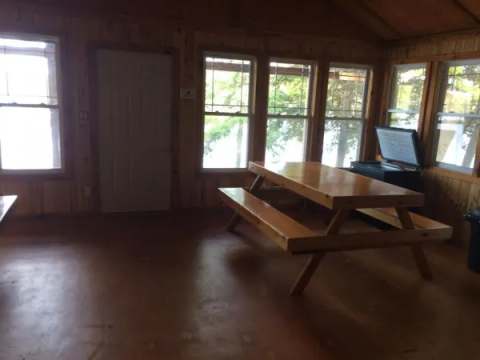 Une table en bois avec bancs est aménagée dans la pièce principale du chalet.