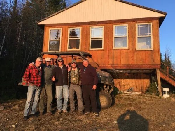 Un groupe de clients pose devant le chalet Trap Lake à la fin d'une journée en forêt.