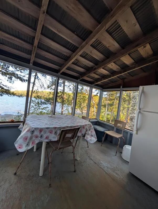 La véranda du chalet offre une table à manger avec une vue directe sur le lac.
