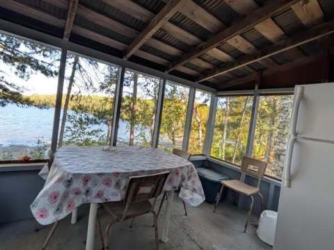 La véranda du chalet offre une table à manger avec une vue directe sur le lac.