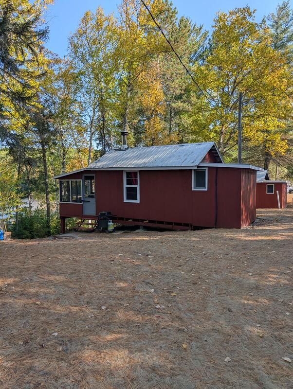 Vue latérale du chalet 4 situé en bordure de forêt avec un terrain dégagé.